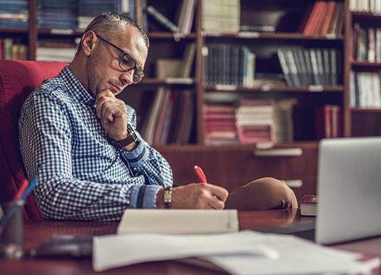 Man writing in front of computer