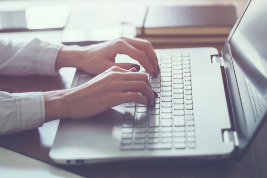 Woman working in home office hand on keyboard close up